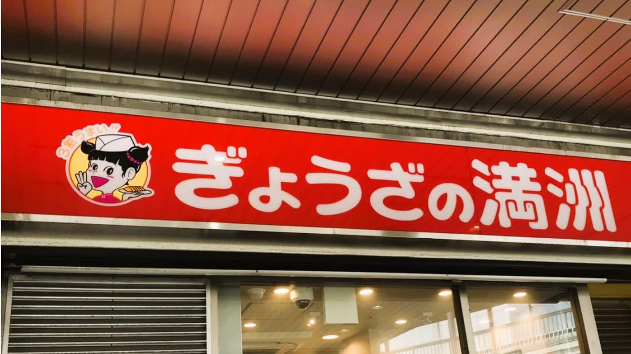 ぎょうざの満洲の店舗看板｜赤い背景にキャラクターと店名